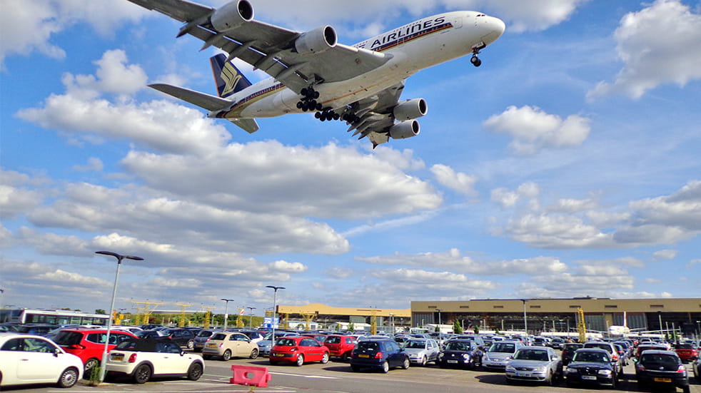 A Singapore Airlines Airbus A380 "Superjumbo" flies over a car park moments before touching down on Runway 27R at London Heathrow Airport 
